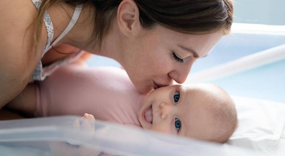 أم تقبّل طفلها حديث الولادة، تعبير عن نجاح الحمل والأمومة بعد علاج الخصوبة