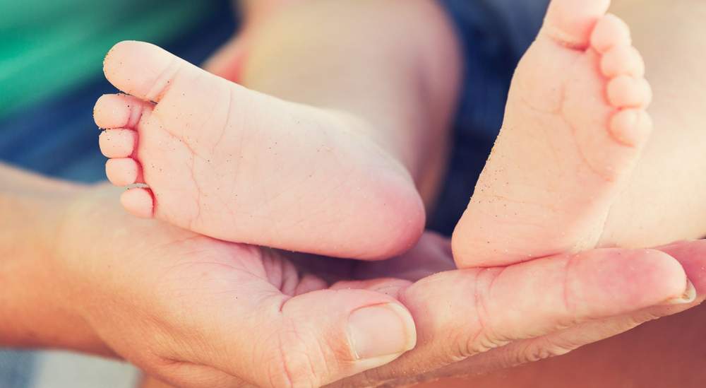 Newborn baby feet held gently in hands, symbolizing successful pregnancy through egg donation and IVF treatment