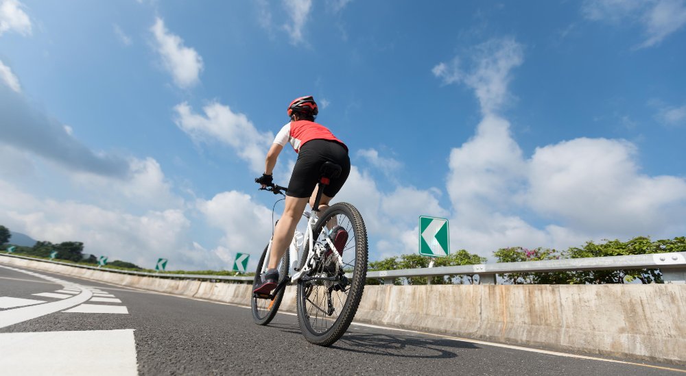 Woman cycling outdoors after childbirth as part of a safe postpartum fitness routine